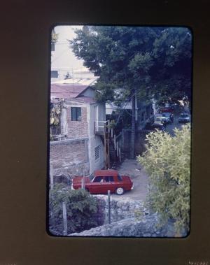 [A Red Automobile Next to a Building]