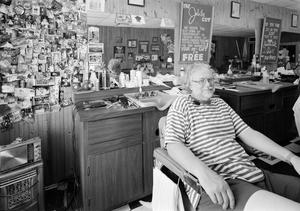 [A man sitting in a chair at a barber shop]