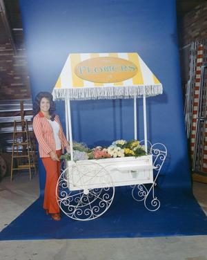[Lynda Arnold posing next to a studio flower stand, 2]