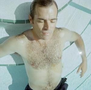 [A man posing in a swimming pool by the steps, 2]