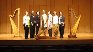 [Members of the American Harp Society standing between three historical harps]