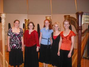[Five women standing in front of harps]