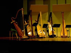 Primary view of object titled '[Four harpists wearing green performing on a stage]'.