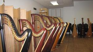 [A row of harps next to cardboard boxes and chairs]