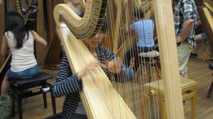 [A girl and two other kids playing harps]