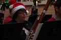 Photograph: [A person playing a bassoon adorned with an ornament and tinsel]