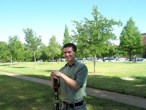[A man in a green shirt and jeans posing with a bassoon]