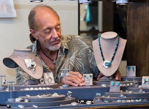 [A man setting up a jewelry shop at the Art Festival]