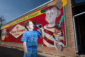 [Kid drinking soda by mural]