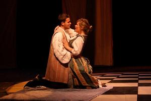 [A man and a woman kneeling and embracing during a stage production]