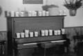 Photograph: [Cups on a piano at the home of Willard Watson, "The Texas Kid", 4]