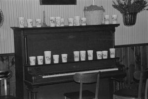 Primary view of object titled '[Cups on a piano at the home of Willard Watson, "The Texas Kid", 5]'.