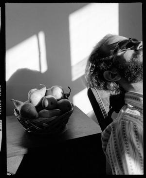 [Man sunbathing next to a bowl of pears]