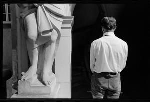 [Man standing at the feet of a statue]