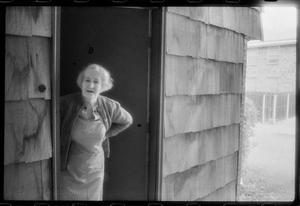 [Elderly woman standing in a doorway]