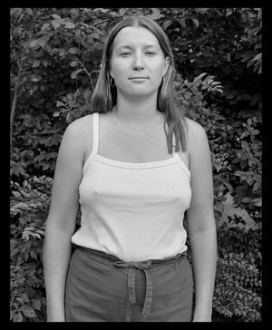 Primary view of object titled '[Woman wearing a tank top and standing in front of a wall of trees]'.