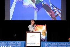[Chad West presenting Dallas rainbow flag]