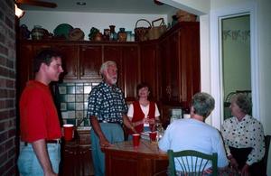 [Five individuals conversing in a kitchen at the Country Place]
