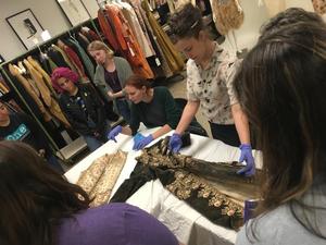 [Students and researchers gathered around an eighteenth-century embroidered menswear]