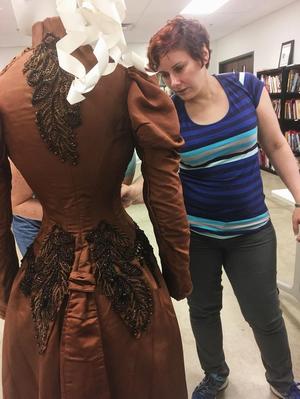 [Ann Medlock studying a nineteenth-century dress]