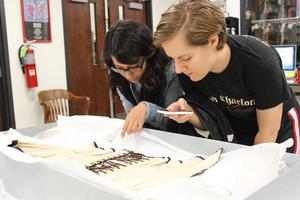 [Two students examining a historic corset]