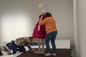 [Janelle McCabe and Annette Becker placing dress on mannequin]