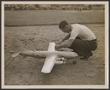 Primary view of [Technician preparing a Forster-powered model airplane outdoors]