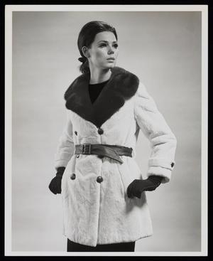 [A model posing in a fur coat with a belt around her waist]