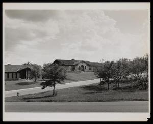 [A street view of two houses on a hill]