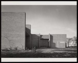 [Exterior view of a brick building surrounded by patchy grass]