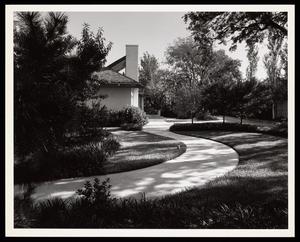 [A walkway leading through grass to a house]