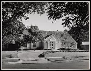 [Exterior of a house with a plant-lined driveway]