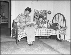 Primary view of [Two girls reading on a bed]