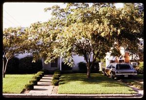 [Mid-century home with a lawn and a car in the driveway]
