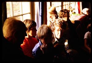 [Adults and children sitting inside a building with windows]