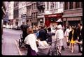 Photograph: [Bustling street with shops and people crossing]