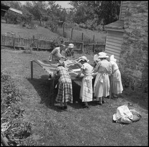 [Women at an outdoor quilting bee]