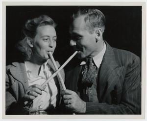 Primary view of object titled '[Couple Sampling Molasses with Sop Sticks]'.