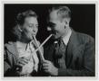 Photograph: [Couple Sampling Molasses with Sop Sticks]