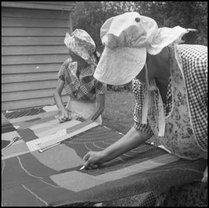 [Women at an outdoor quilting bee]