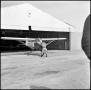 Photograph: [AFROTC member pushing a plane back into a hanger]