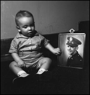 [Baby sitting with a framed photograph]