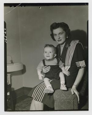 [Photograph of a woman sitting with her baby in her lap]