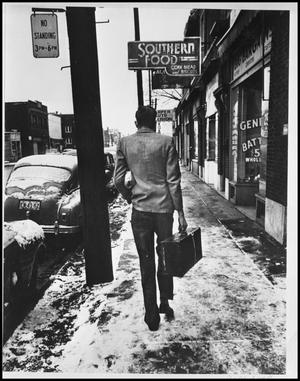 [Photograph of a man walking down an icy sidewalk]