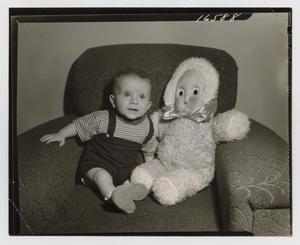 [Photograph of a baby and a doll sitting in a chair]