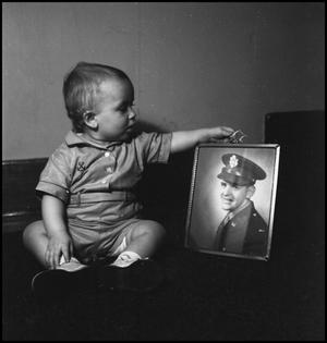 [baby examining the frame of a photograph]