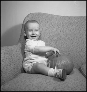 [Baby sitting on a couch with a pumpkin]