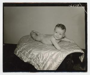 [Photograph of a naked baby lying on a quilt]