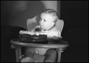 [Baby sitting in a highchair eating cake]
