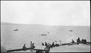 [Photograph of a crowd of people sitting on a dock, 2]